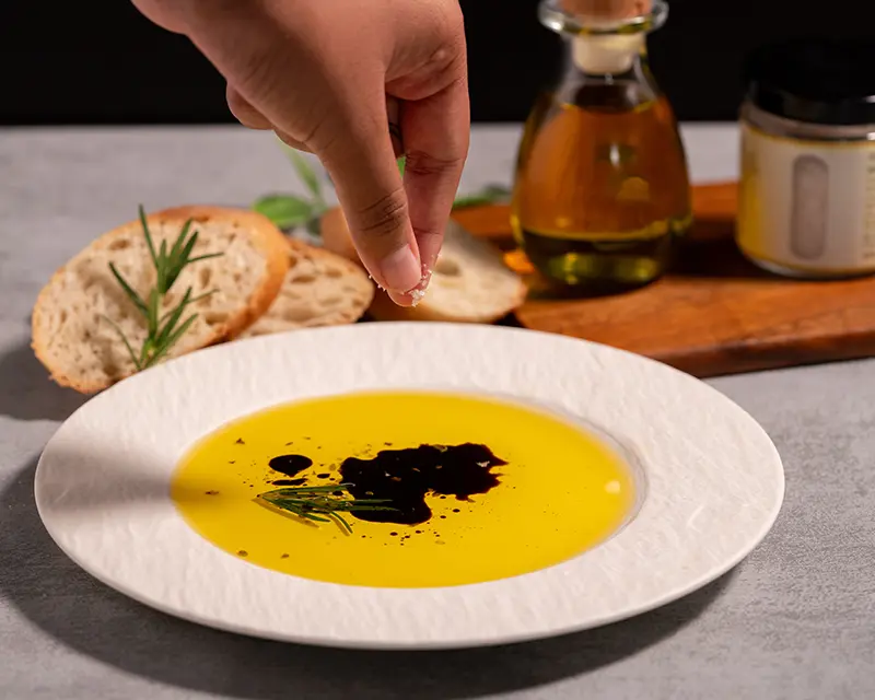 Best salt for olive oil bread dip added to olive oil with baguette and herbs.