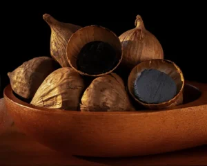Black garlic used for black garlic salt, with one bulb cut open to show the dark aged interior