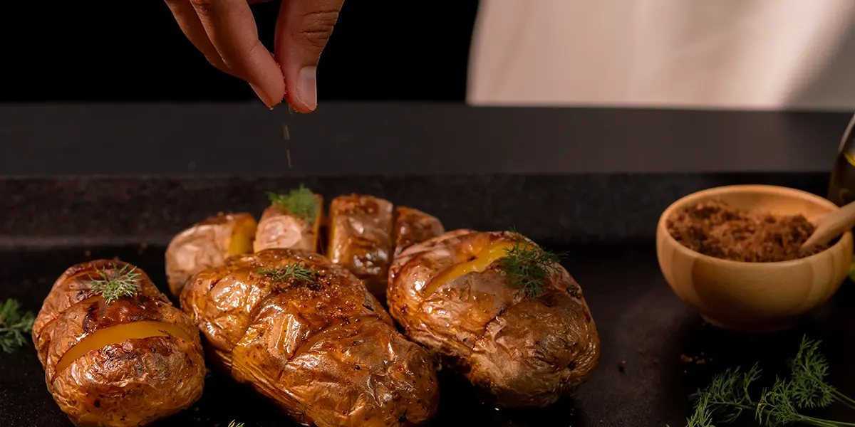 Black garlic salt being sprinkled over warm roast potatoes