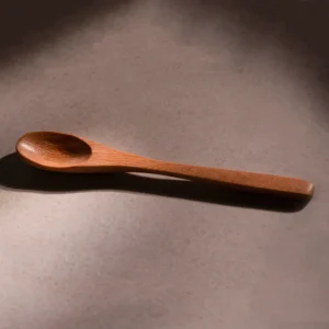 Handmade wooden salt spoon on a warm stone surface