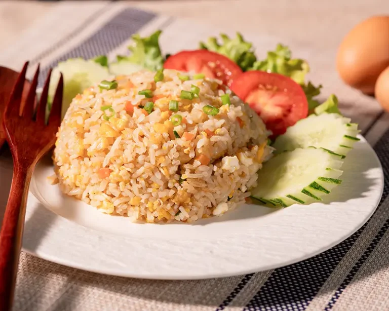 How to salt rice shown as finished fried rice served with cucumber, tomato, herbs, and egg