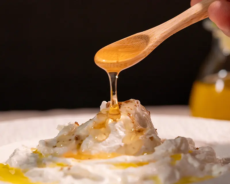 Honey being drizzled over Greek yogurt, showing how to salt yogurt lightly when served sweet.