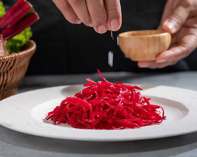 How to season beets with a finishing pinch of salt over grated raw beet