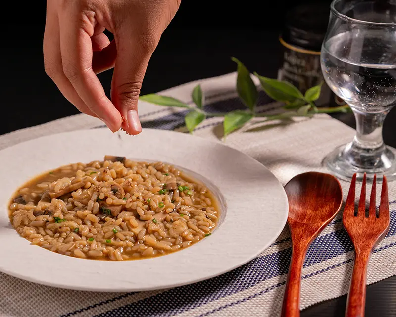 Adding finishing salt to risotto after tasting and deciding how to season risotto