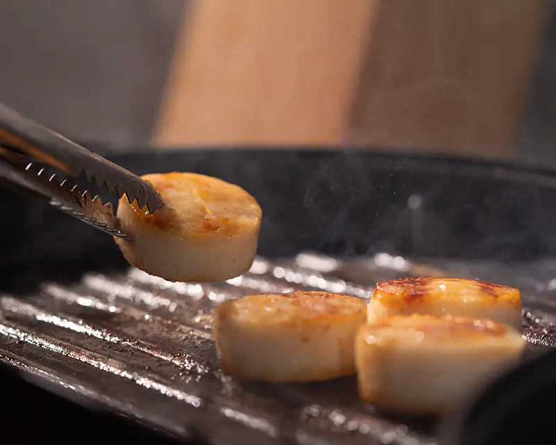 How to season scallops by searing them over high heat until a golden crust forms.