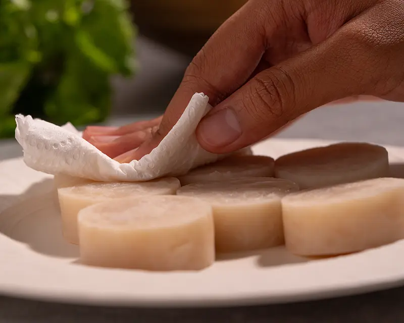How to season scallops by patting away surface moisture after salting before searing.