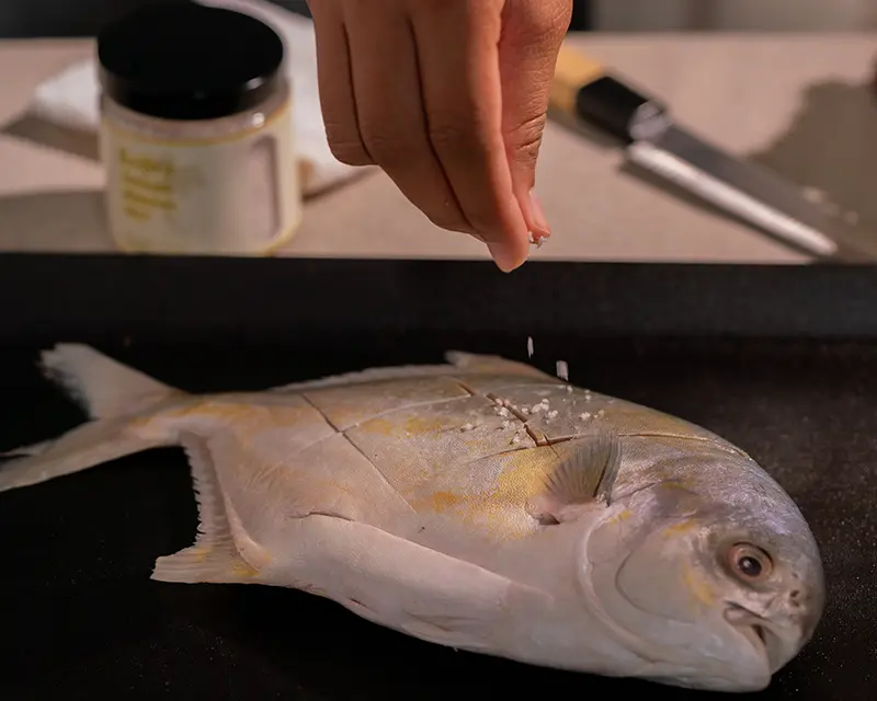 How to season whole fish by lightly salting the scored skin before cooking.