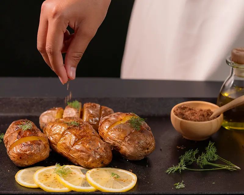 Black garlic salt being added to roast potatoes in an MSG vs umami comparison