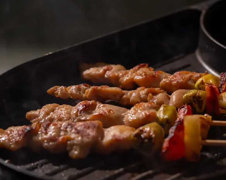 Chicken skewers browning in a hot pan, showing how salt affects browning through surface moisture, heat, and timing.