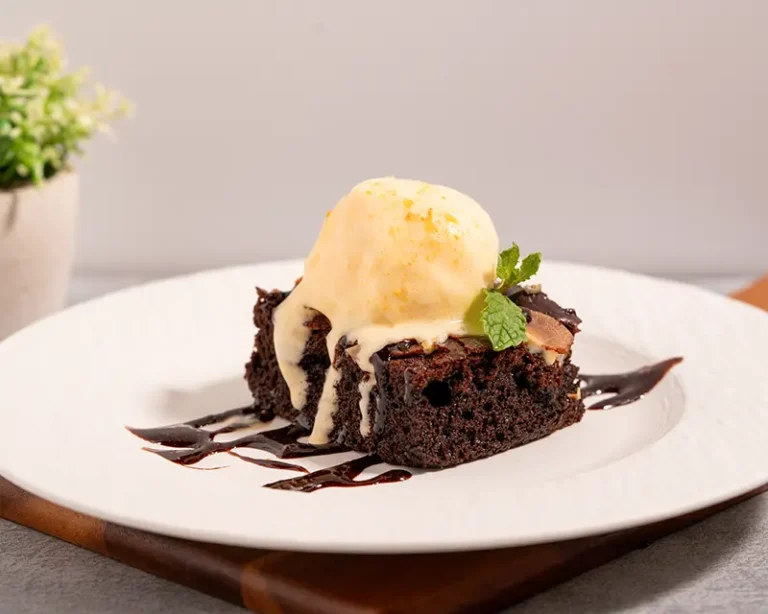 Salt on desserts with chocolate brownie, melting ice cream and chocolate sauce on a white plate