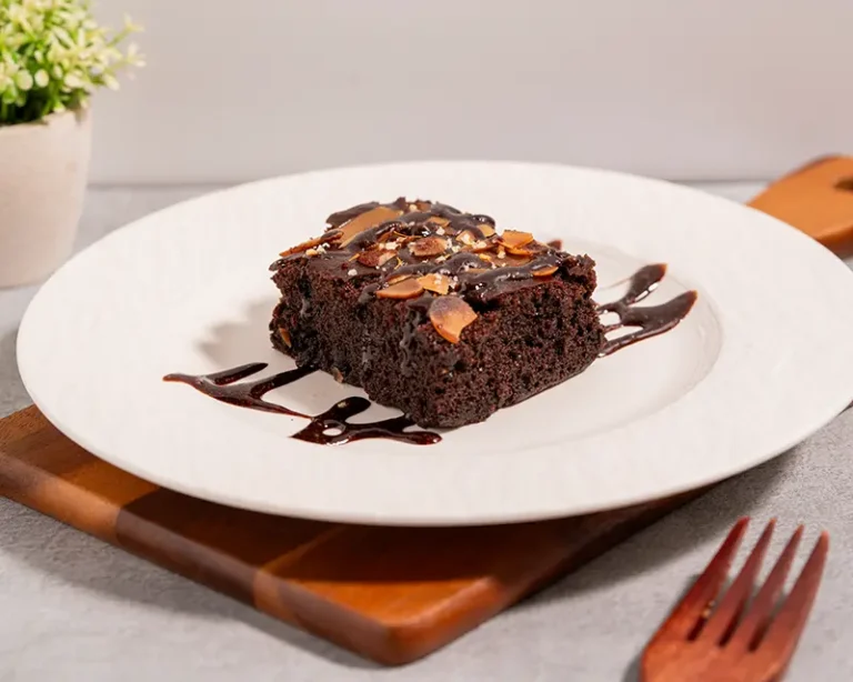Salt on desserts with chocolate brownie, almonds, chocolate sauce and finishing salt on a white plate