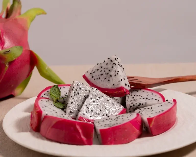 Salt on fruit with sliced dragon fruit, mint and wooden fork on a white plate