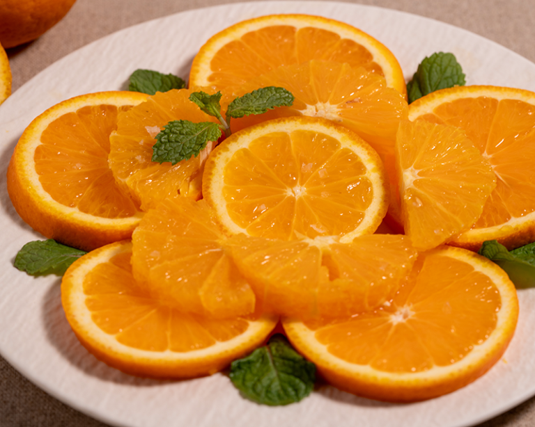 Salt on fruit with sliced oranges, mint and sea salt on a white plate