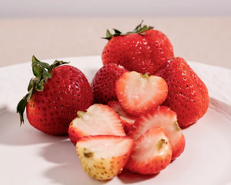 Salt on fruit with ripe strawberries and a tiny pinch of mineral salt