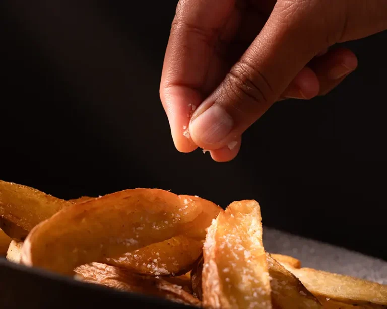 finishing salt being sprinkled over hot potatoes to create surface flavour contrast