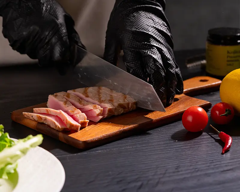 Chef slicing seared tuna steak to reveal its pink centre before adding the final pinch of salt for tuna steak seasoning.