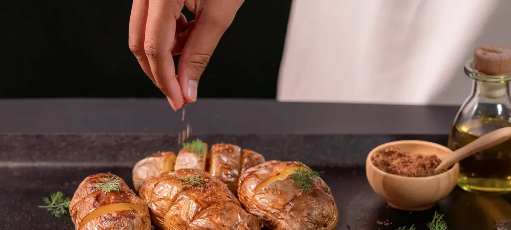 Roast potatoes being finished with salt for a guide on when to salt potatoes.