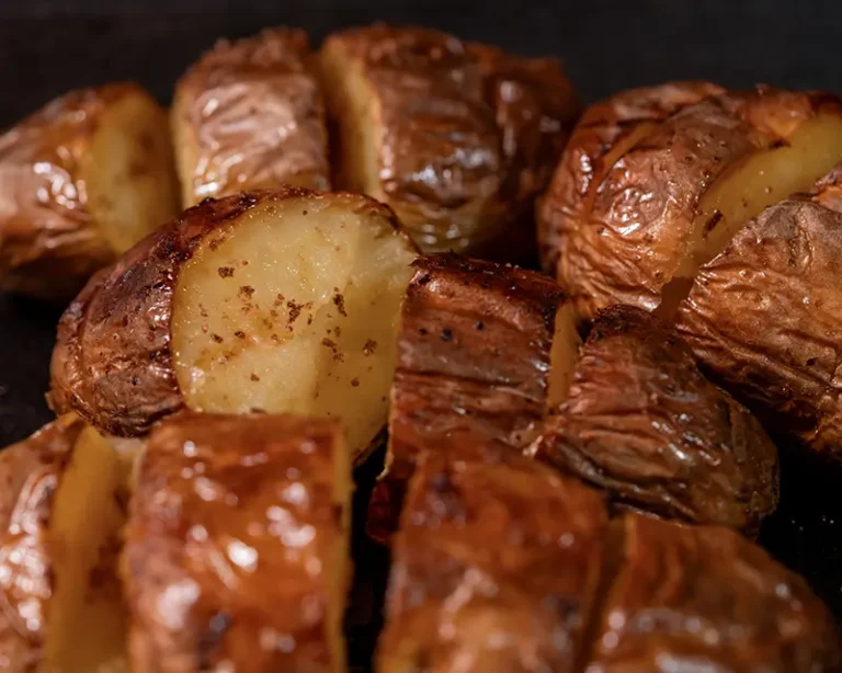 Opened roast potatoes finished with black garlic salt while still hot, showing when to salt roast potatoes for a crisp edge and seasoned centre.