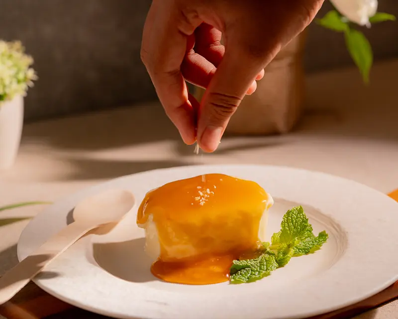 Salt sprinkled over caramel pudding to show why salt makes food taste better in sweet dishes.